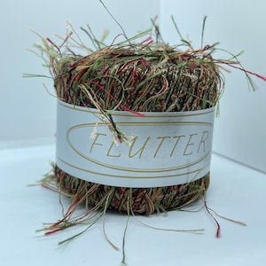 May include: A spool of green, red, and brown yarn with a white label that says "FLUTTER".