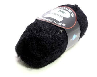 Könnte beinhalten: Eine schwarze Garnrolle mit einem weißen Etikett, auf dem "Enchanting Horse Yarns" steht.