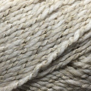 May include: Close-up of a beige yarn with gold metallic threads woven throughout.