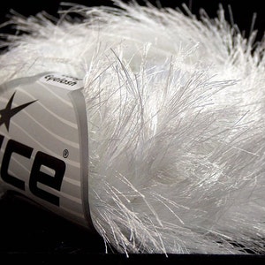 May include: A white ball of yarn with a label that says "Ice Eyelash" with a star and the word "Ice" in black.