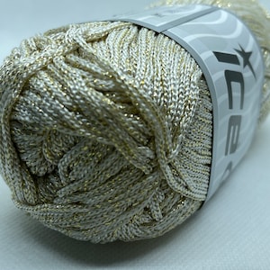 Op de afbeelding: Een bol wit en goud metallic garen met een label met de tekst "Ice Yarns".