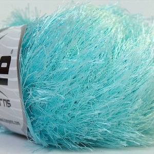 Puede incluir: Un ovillo de hilo azul claro y esponjoso con la etiqueta "Ice Yarns" en él.