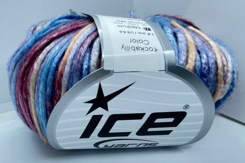 May include: A skein of variegated yarn featuring a blend of blue, purple, red, and beige tones. The yarn is wrapped in a white paper label with the text Ice Yarns, Rockabilly Color, and technical specifications including 4.5-5.5 mm needle size.