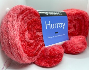 May include: Two skeins of red and pink yarn with a label that reads "Hurray" and "Visit us at www.berroco.com".