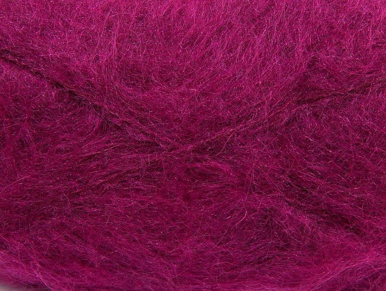 May include: Close-up of a vibrant magenta yarn, showcasing a soft, textured appearance. The yarn fibers are densely packed, creating a plush, inviting look. This yarn is suitable for various knitting and crochet projects.