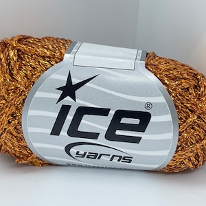 May include: A ball of metallic gold yarn with a label that reads "ICE YARNS". The yarn has a shiny, textured appearance. The label is silver and white with a black star and the word "ICE" in large letters.