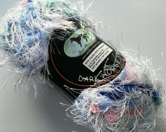 May include: A skein of blue, pink, and green yarn with white fuzzy fibers. The yarn label reads "Dark Horse Yarn" and includes information about the yarn's composition, gauge, needle size, and yardage.