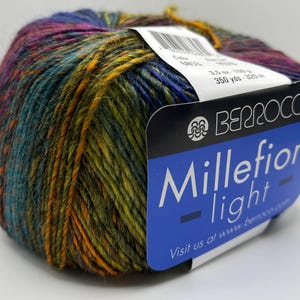 May include: A ball of Berroco Millefiori Light yarn in a mix of colours including blue, green, purple, and orange. The label displays "Millefiori light" and "3.5 oz - 100 g". This yarn is suitable for knitting and crochet projects, with 320 meters of yarn.