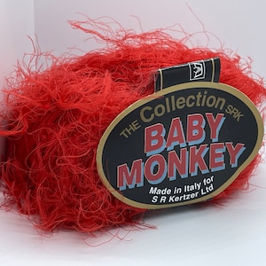 May include: A ball of red fuzzy yarn with a label that reads "The Collection SRK Baby Monkey Made in Italy for SR Kertzer Ltd."