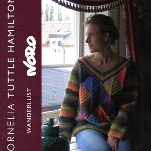 May include: A woman wearing a colourful knitted jumper with a geometric pattern sits by a window. The jumper has stripes and a patchwork design. The text "Wanderlust" and "more" is visible on the left side of the image.
