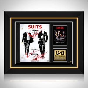 May include: Framed "Suits" memorabilia, including a script page titled "PILOT" with signatures, a show poster, and a USA Network logo. The frame is black with a gold inner border.