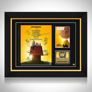 Puede incluir: Recuerdos enmarcados de la película Peanuts. El marco tiene un borde negro con un borde interior dorado. La pantalla incluye un cartel de la película, una página del guion con firmas y una placa de 20th Century Fox. La página del guion dice "DREAM BIG".