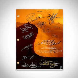 May include: A signed script from the film Dune, featuring the signatures of the cast and crew. The script is set against a background of a desert landscape with a dune in the foreground. The text on the script reads "IT BEGINS." "SCREENPLAY BY JON SPAIHTS." "DENIS VILLENEUVE." "ERIC ROTHE." "BASED ON DUNE." "BY FRANK HERBERT." "JUNE 19, 2020 SALINATVISIONS." "FINAL SHOOTING DRAFT."