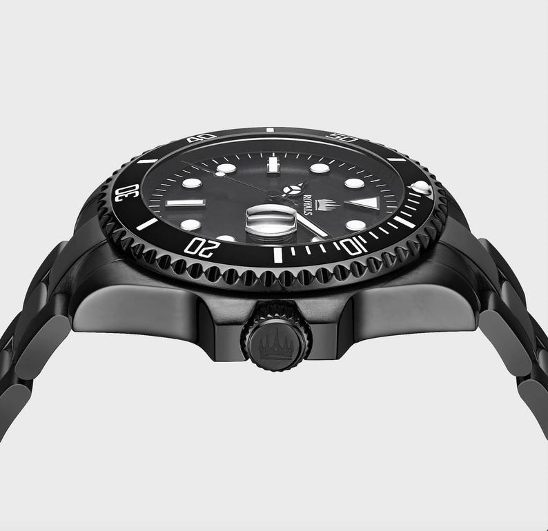May include: A black stainless steel watch with a black dial and white markings. The watch has a rotating bezel with white numbers and a date window at the 3 o'clock position. The watch is on a black stainless steel bracelet.