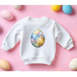 May include: White sweatshirt with a colorful, ornate Easter egg design on the front.