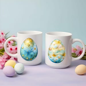 May include: Two white ceramic mugs with handles. One mug features a blue and gold egg with a watercolor design. The other mug features a gold and blue egg with a swirling pattern.