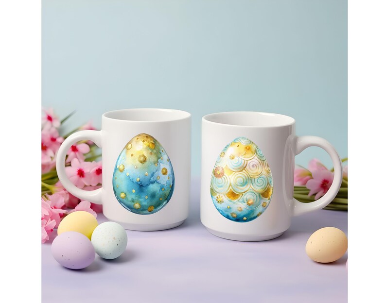 May include: Two white ceramic mugs with handles. One mug features a blue and gold egg with a watercolor design. The other mug features a gold and blue egg with a swirling pattern.