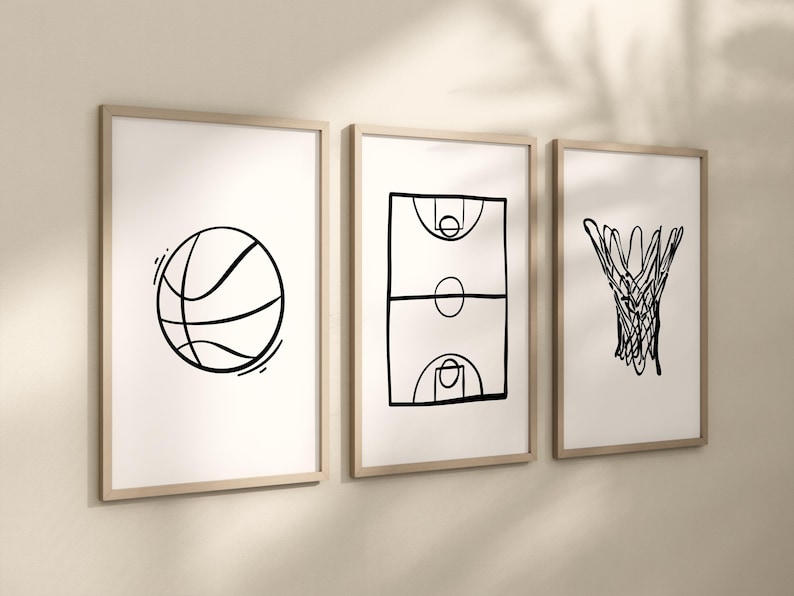 May include: Three framed art prints with basketball-themed line drawings. The prints feature a basketball, a basketball court, and a basketball net, all in black on a white background. The frames are a light wood color.