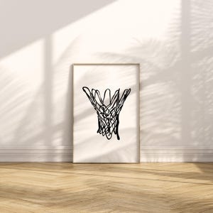 May include: A framed print featuring a black line drawing of a basketball net. The artwork is displayed against a white wall with shadows and a wooden floor. The minimalist design adds a modern touch to the space.