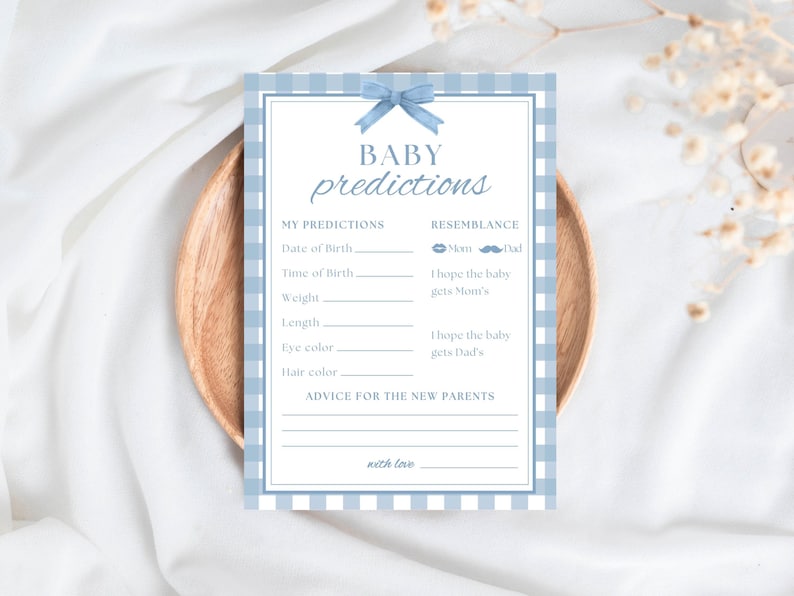 K&ouml;nnte beinhalten: Eine Babyparty-Spielkarte mit dem Schriftzug "BABY predictions" in Schreibschrift. Die Karte hat einen blau-wei&szlig; karierten Rand und eine blaue Schleife oben. Sie enth&auml;lt Abschnitte f&uuml;r Vorhersagen &uuml;ber die Geburt und die &Auml;hnlichkeit des Babys.