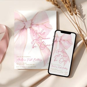 May include: A pink and white invitation and a smartphone displaying the same design. The design features a watercolor bow and the text "Girls just wanna be One" and "Amelia's First Birthday". The invitation includes address and RSVP information.