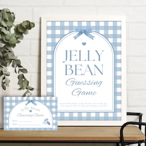 Op de afbeelding: Een ingelijst bord en bijpassende kaart voor een "Jelly Bean Guessing Game" in een lichtblauw ruitpatroon. Het bord toont de tekst "Jelly Bean Guessing Game" met een strik en hart ontwerp. Een vaas met groen staat links.