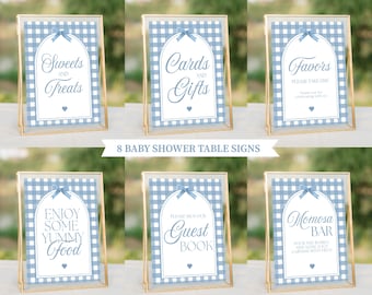 May include: Eight blue and white gingham baby shower table signs with gold frames. The signs include the text: "Sweets and Treats", "Cards and Gifts", "Favors Please Take One", "Enjoy Some Yummy Food", "Please Sign Our Guest Book", and "Mimosa Bar".