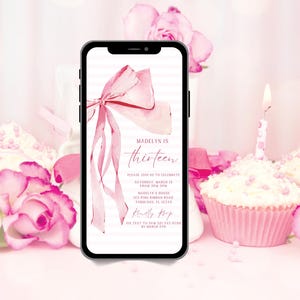 May include: A smartphone displays a pink birthday invitation with a watercolor bow and the text "Madelyn is thirteen." The invitation includes event details and a request to RSVP via text. Cupcakes and pink roses surround the phone.