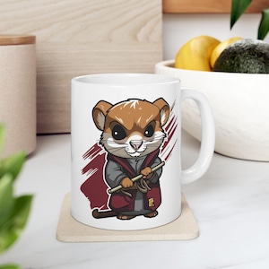 May include: White ceramic mug with a brown and white cartoon image of a rodent wearing a red and gray robe and holding a stick. The rodent has a serious expression and is holding the stick in a fighting stance.