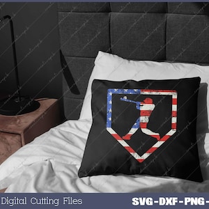 Pode incluir: Uma almofada preta com uma silhueta de jogador de beisebol num diamante de beisebol. O diamante est&aacute; preenchido com as cores da bandeira americana, vermelho, branco e azul.