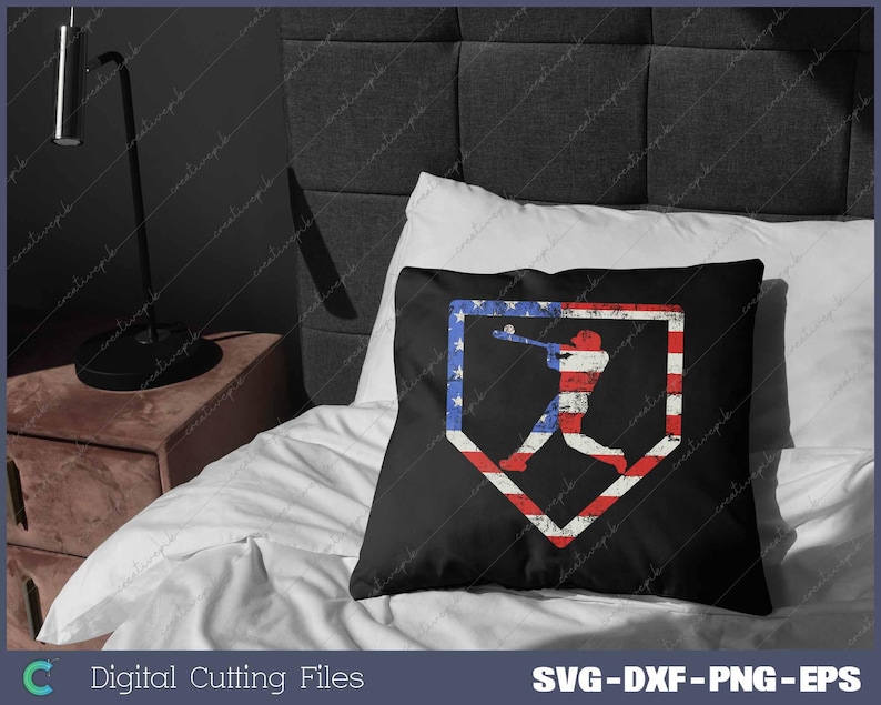 Pode incluir: Uma almofada preta com uma silhueta de jogador de beisebol num diamante de beisebol. O diamante est&aacute; preenchido com as cores da bandeira americana, vermelho, branco e azul.