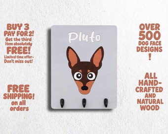 May include: A gray wooden key holder with three hooks. The key holder features a cartoon illustration of a brown and black dog with the name "Pluto" printed above the dog.