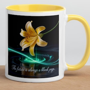 Könnte beinhalten: Weiße Keramiktasse mit gelbem Innenraum und Griff. Die Tasse zeigt ein Blumendesign mit einer gelben Lilie und dem Text "The future is always a blank page" auf schwarzem Hintergrund.