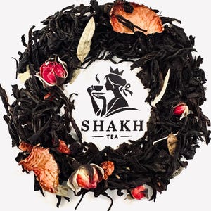 May include: Black tea blend with dried rose petals, fruit pieces, and white tea leaves. The tea is arranged in a circle around a logo that says "Shakh Tea".