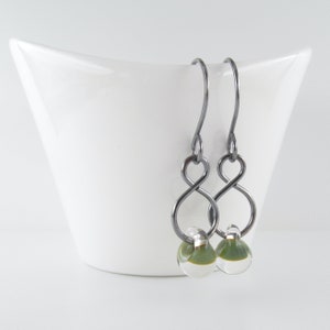 May include: A pair of silver infinity earrings with green and clear glass beads.