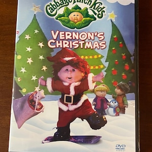 May include: A Cabbage Patch Kids DVD titled Vernon's Christmas featuring a doll dressed as Santa Claus on a snowboard, a sack of toys, and two other dolls in a snowy landscape with decorated Christmas trees and the text A CLASSIC HOLIDAY STORY.