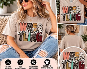 May include: A beige short-sleeve t-shirt featuring the word WRESTLING in large, colorful block letters with a leopard print pattern on some letters, overlaid with the word wrestling in a white cursive script font across the center.