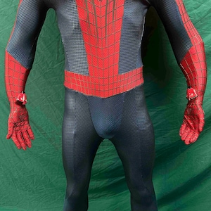 May include: A full-body spandex suit featuring a dark blue textured base with a red chest panel and red sleeves, both overlaid with a black web pattern. The suit includes red gloves with black webbing and small red mechanical wrist attachments.