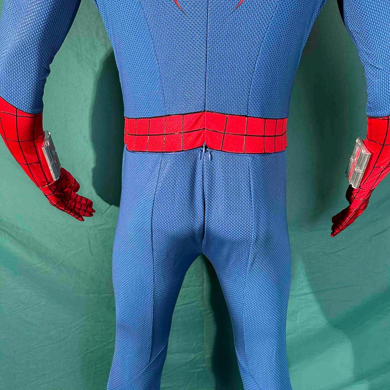 Puede incluir: Traje de superh&eacute;roe azul y rojo. El disfraz presenta un body azul con un patr&oacute;n texturizado, detalles rojos en los guantes y el cintur&oacute;n, y un dise&ntilde;o de telara&ntilde;a roja en los guantes. Los guantes tienen accesorios plateados.