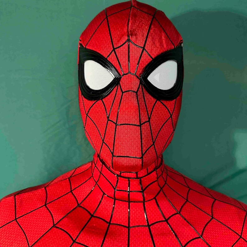 Puede incluir: Una m&aacute;scara de Spider-Man roja y negra con lentes oculares blancas. La m&aacute;scara presenta un patr&oacute;n de telara&ntilde;a y est&aacute; hecha de un material texturizado. La imagen es un primer plano, que muestra los detalles del dise&ntilde;o.