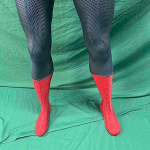 May include: A pair of leggings featuring a dark blue upper section with a textured honeycomb pattern and a bright red lower section adorned with a black web-like grid design that extends down to cover the feet in a fitted, full-length style.