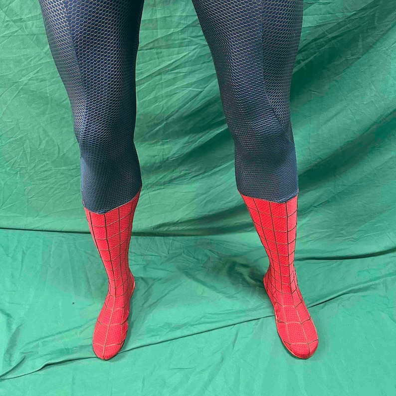 May include: A pair of leggings featuring a dark blue upper section with a textured honeycomb pattern and a bright red lower section adorned with a black web-like grid design that extends down to cover the feet in a fitted, full-length style.