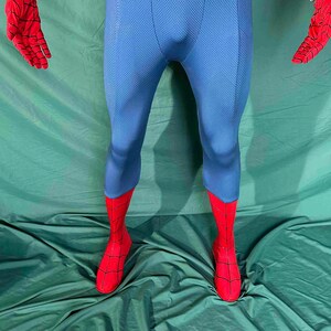 Puede incluir: Un disfraz de superh&eacute;roe azul y rojo. El disfraz presenta un body azul con detalles rojos en los pies y las manos. Los guantes y las botas rojas tienen un dise&ntilde;o de telara&ntilde;a. El disfraz est&aacute; hecho de una tela texturizada.