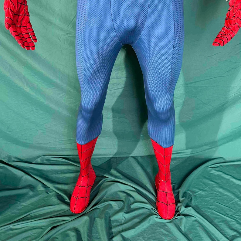 Puede incluir: Un disfraz de superh&eacute;roe azul y rojo. El disfraz presenta un body azul con detalles rojos en los pies y las manos. Los guantes y las botas rojas tienen un dise&ntilde;o de telara&ntilde;a. El disfraz est&aacute; hecho de una tela texturizada.
