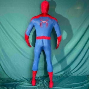 Puede incluir: Un disfraz de Spider-Man azul y rojo. El disfraz presenta una capucha, hombros, guantes y botas rojas. El torso y las piernas son azules, con un emblema de ara&ntilde;a roja en la espalda. El disfraz tiene un dise&ntilde;o ajustado.