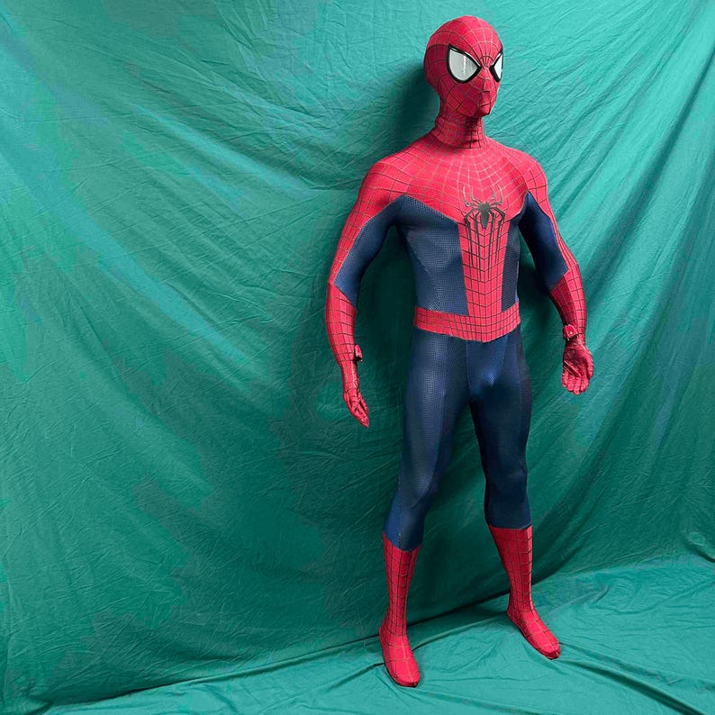 May include: A full-body Spiderman costume featuring a red and blue color scheme with a black spider emblem on the chest. The suit includes a textured fabric pattern, a full-head mask with white eye lenses, and integrated gloves and foot coverings.