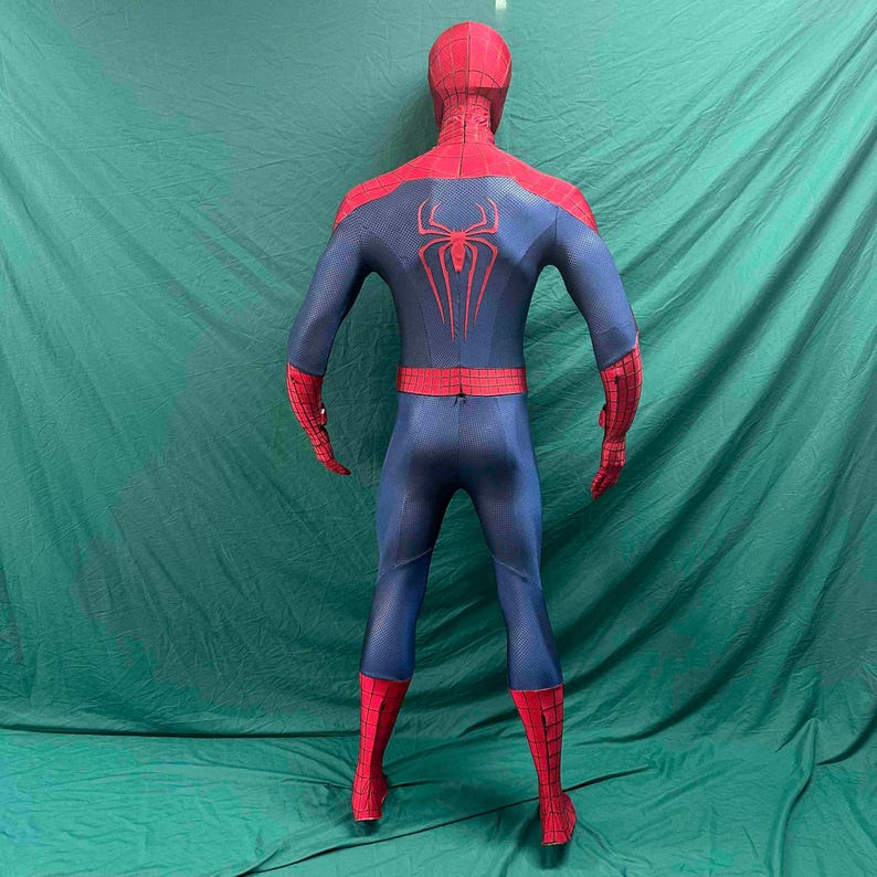 May include: A full-body spandex costume featuring a red and blue color scheme with a black web pattern. The back displays a large red spider emblem centered on the blue torso section, with red sleeves and leggings featuring a grid-like design.