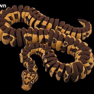 May include: A segmented snake toy in shades of brown and yellow, with a pattern resembling a clown's markings. The toy is coiled against a black background, with the word "Clown" in the upper left corner.