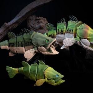 May include: Three articulated fish figures with segmented bodies, green and tan scales, and open mouths. The figures feature detailed fins and eyes, with two positioned higher and one lower, all displayed against a dark background.