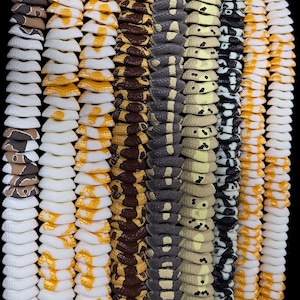 May include: A vertical arrangement of several decorative snake-like items. The items are in various colors and patterns, including white, yellow, brown, gray, and black. The items have a segmented design, resembling a snake's body.